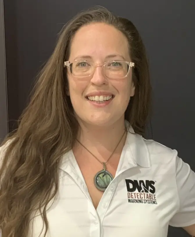 Close-up portrait of team member with glasses, smiling in corporate environment.