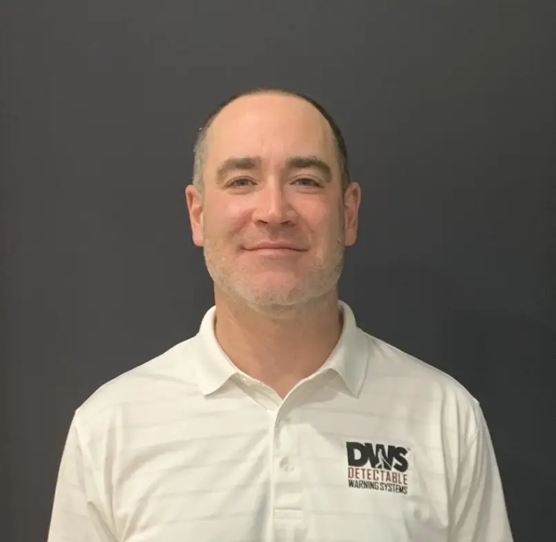 Headshot of team member in creative role, wearing casual attire with modern background.