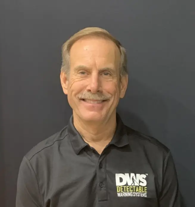 Portrait of team member in formal attire smiling confidently against office background.